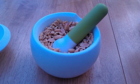 Crush peanuts in pestle and mortar